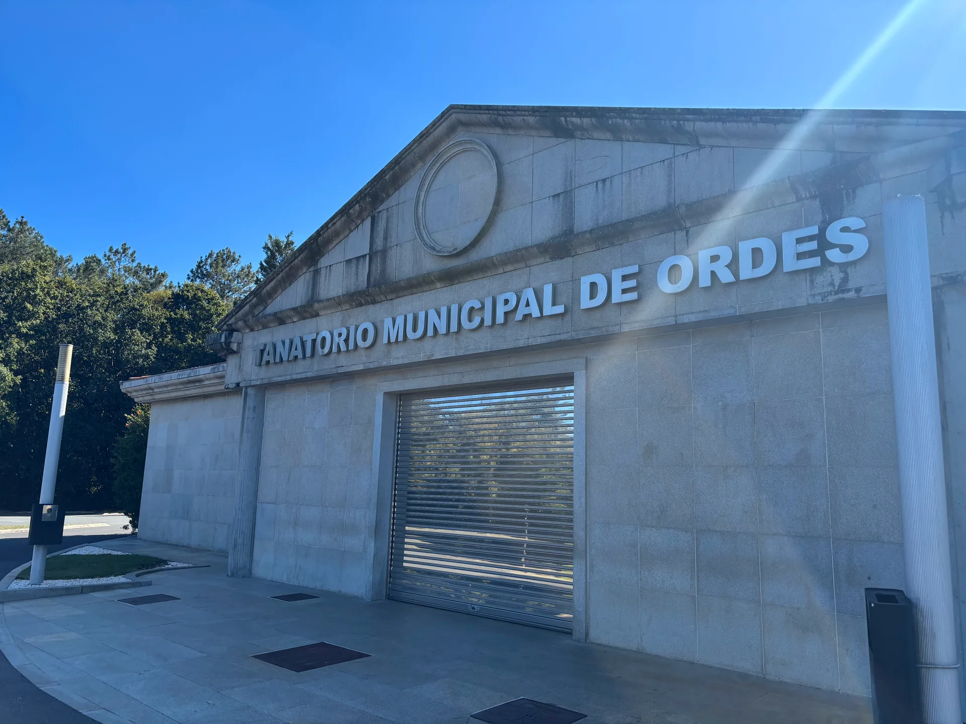 Fachada del Tanatorio Municipal de Ordes con el rótulo «Tanatorio Municipal de Ordes» bajo el frontón y la puerta de acceso